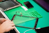 Primer plano de la reparación del hombre tableta digital en el centro de reparación - foto de stock