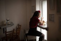 Frau schaut durch Fenster, während sie einen Salat im Café isst — Stockfoto