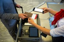Personal femenino del aeropuerto que usa teléfono móvil para escanear el pasaporte en la terminal del aeropuerto - foto de stock