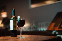 Glas Rotwein und Flasche auf Theke an der Bar — Stockfoto