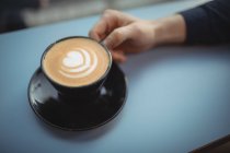 Mano de hombre ejecutivo sosteniendo taza de café en la cafetería - foto de stock
