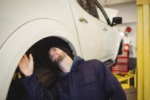 Mechanic examining a car wheel disc brake in repair garage — Stock Photo
