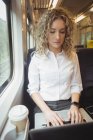 Empresária loira usando laptop enquanto viaja — Fotografia de Stock