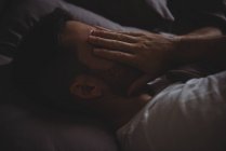 Primo piano dell'uomo che strofina gli occhi mentre dorme nel suo letto a casa — Foto stock