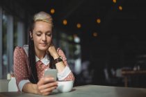 Frau benutzt Handy beim Kaffeetrinken im Café — Stockfoto