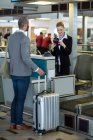 Pendolari in piedi al banco mentre controllano il passaporto al terminal dell'aeroporto — Foto stock
