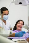 Dentiste tenant miroir devant le patient à la clinique — Photo de stock