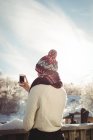 Rückansicht einer Frau, die im Skigebiet mit dem Handy fotografiert — Stockfoto