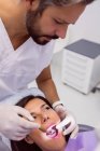 Dentist examining female patient teeth with mouth mirror in clinic — Stock Photo
