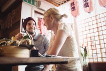Casal interagindo uns com os outros enquanto toma chá no restaurante — Fotografia de Stock
