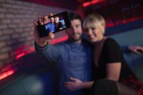 Sorrindo casal tirando selfie no celular no bar — Fotografia de Stock