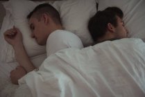 High angle view of gay couple sleeping together on bed — Stock Photo