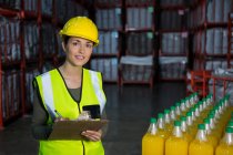 Молодая работница проверяет бутылки сока на заводе — стоковое фото