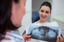 Dentista discutendo con paziente sopra rapporto dei raggi X nella clinica estetica — Foto stock