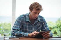 Mann sitzt am Schreibtisch und nutzt digitales Tablet zu Hause — Stockfoto