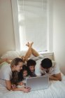Щаслива сім'я використовує ноутбук у спальні вдома — стокове фото