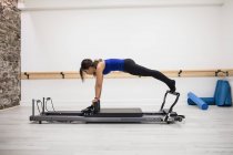 Woman exercising on reformer equipment in gym — Stock Photo