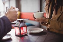 Seção média de casal segurando xícaras de café no restaurante — Fotografia de Stock