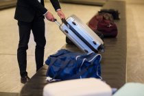 Businessman picking his luggage from baggage claim area at airport — Stock Photo