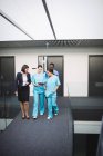 Doctor and nurses discussing over digital tablet while walking in hospital corridor — Stock Photo