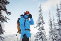 Skier talking on mobile phone on snow covered landscape — Stock Photo