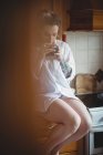 Женщина сидит и пьет кофе на кухне дома — стоковое фото
