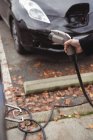Рука человека держит зарядное устройство автомобиля на электростанции зарядки автомобиля — стоковое фото