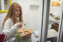 Mujer joven comiendo ensalada en el restaurante - foto de stock