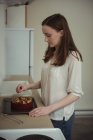 Женщина глазурь торт с сахаром на кухне дома — стоковое фото