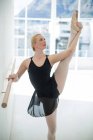 Балерина растягивается на барре во время репетиции балетных танцев в студии — стоковое фото