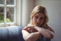 Retrato de mulher pensativa sentada no sofá na sala de estar — Fotografia de Stock