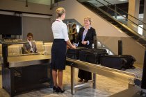 Geschäftsfrau interagiert mit Flughafenpersonal mit Gepäck am Fließband im Flughafenterminal — Stockfoto
