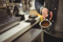 Meados de seção de homem segurando portafilter com café moído no café — Fotografia de Stock