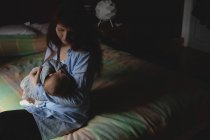 Мать кормит грудью младенца в спальне дома — стоковое фото