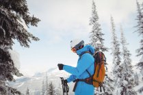 Skifahrer steht und schaut auf die Karte in verschneiter Landschaft — Stockfoto