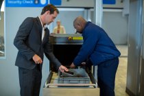 Сотрудник службы безопасности аэропорта проверяет багаж пассажира в терминале аэропорта — стоковое фото