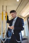 Бизнесмен слушает музыку и пользуется мобильным телефоном в поезде — стоковое фото