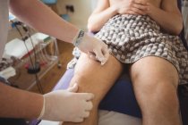 Physiothérapeute pratiquant l'aiguille sèche sur le genou d'un patient de sexe masculin en clinique — Photo de stock