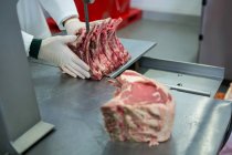 Крупный план мясника, режущего мясо с помощью машины для резки мяса — стоковое фото