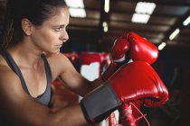 Задумчивая женщина-боксер опирается на боксерское кольцо в фитнес-студии — стоковое фото