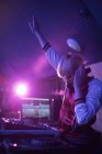 Jolie DJ féminine avec bras levé tout en jouant de la musique dans le bar — Photo de stock
