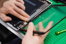 Nahaufnahme eines Mannes, der den Bildschirm eines digitalen Tablets im Reparaturzentrum repariert — Stockfoto