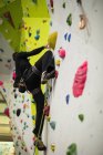 Uomo che pratica arrampicata su parete artificiale in palestra — Foto stock