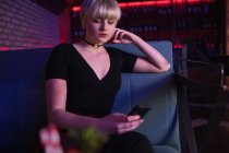 Красива жінка використовує мобільний телефон в барі — стокове фото
