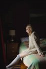 Donna seduta sul letto in camera da letto — Foto stock