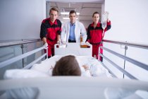 Medici che spingono letto barella di emergenza in corridoio in ospedale — Foto stock