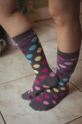 Pés femininos vestindo bolinhas multicoloridas meias em casa — Fotografia de Stock