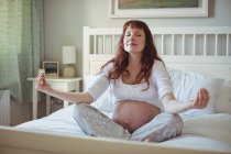 Schwangere macht Yoga auf Bett im Schlafzimmer — Stockfoto