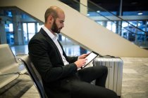 Бизнесмен с помощью цифрового планшета в аэропорту — стоковое фото