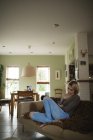 Frau liegt und benutzt Handy auf Couch im Wohnzimmer — Stockfoto